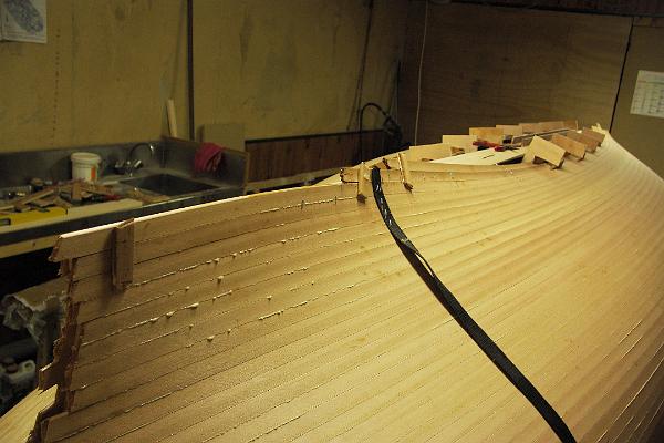 PICT3154.JPG - La fin de lattage à l'arrière est facilitée par quelques agrafes, posées ici sur une sangle, qui permettra de les enlever d'un coup. Quelques chutes de lattes et de la colle thermofusible aident aussi au maintien des lattes adjacentes entre elles aux extrémités.